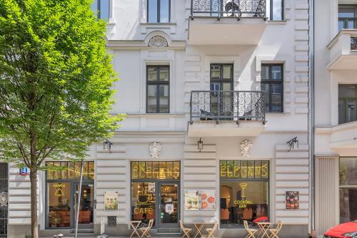 a white building with tables and chairs in front of it at WSCHODNIA ELEGANS Aparthotel in Łódź