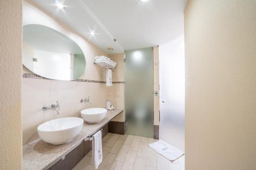 ein Badezimmer mit zwei Waschbecken und einem Spiegel in der Unterkunft Hotel Abastos Plaza in Mexiko-Stadt