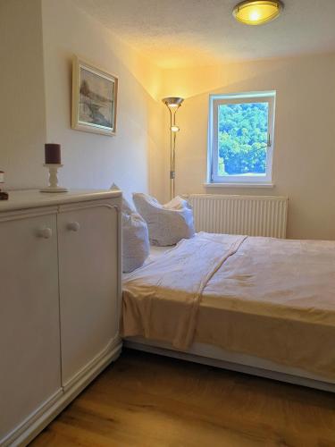 a bedroom with a bed with a dresser and a window at Elbblick-kleine-Wohnung-mit-Terrasse in Gollhofen