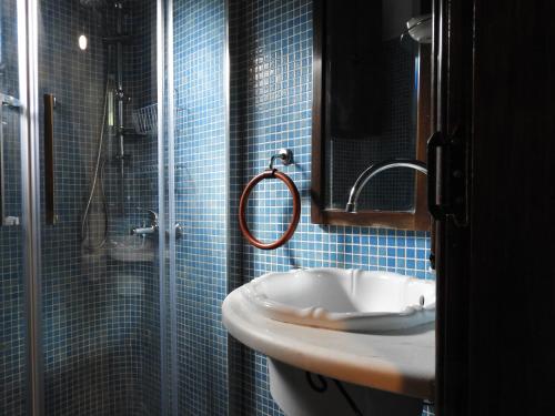 a blue tiled bathroom with a sink and a shower at Olivia traditional stone house in Nikiti