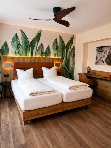 a bedroom with two beds and a painting of leaves at Hotel-Restaurant Amadeus in Hannover