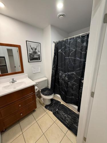 a bathroom with a black shower curtain and a toilet at Downtown Studio for 2 with Free private parking in Montreal
