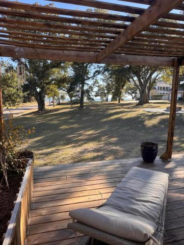 a wooden deck with a bench under a wooden pergola at Steps from beach with open fire pit in Gulfport