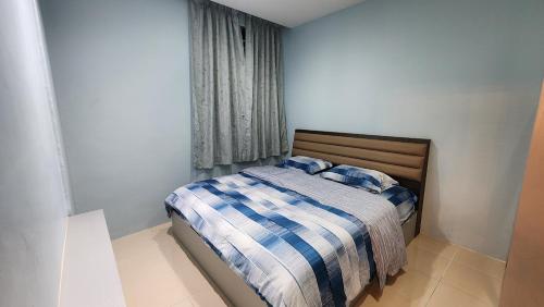 a bedroom with a bed with a blue and white blanket at Centrum Homstay at Crown Imperial Court in Cameron Highlands