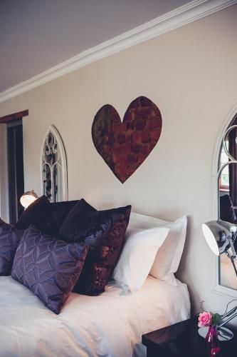 a heart on the wall above a bed with pillows at Station House Simondium in Simondium