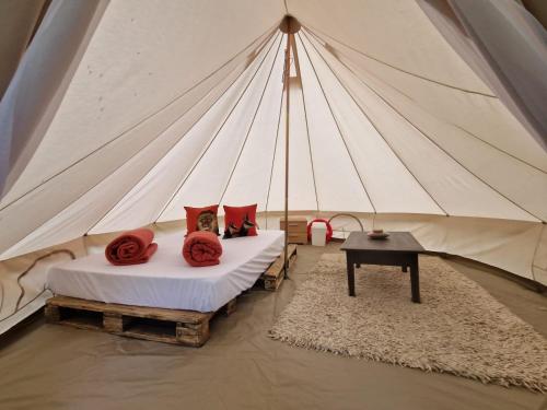 a tent with two beds with red pillows and a table at Ferme équestre de la Molière in Naves