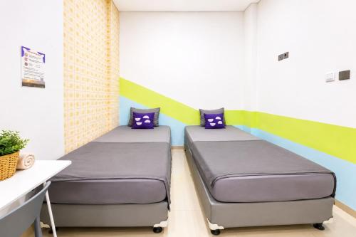 two beds in a room with a desk at Monggo Mampir Tanjung Duren By Reccoma in Jakarta