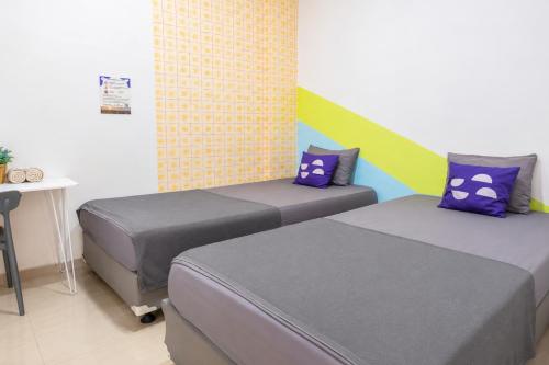 two beds in a room with a desk and a table at Monggo Mampir Tanjung Duren By Reccoma in Jakarta