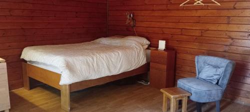a bedroom with a bed and a blue chair at Retraitehuisje Westerwolde in Blijham