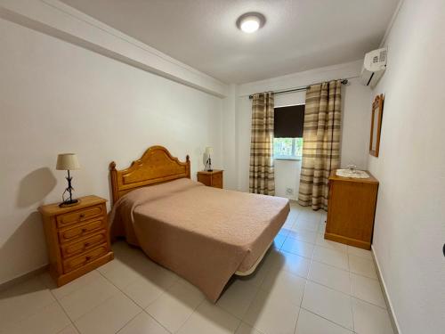 a bedroom with a bed and a dresser and a window at Edificio Fragata A in Armação de Pêra