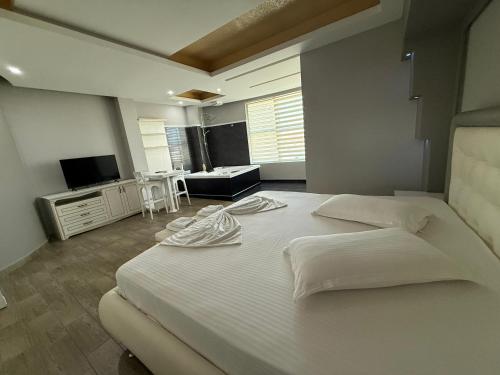 ein Schlafzimmer mit einem großen weißen Bett und einem Fernseher in der Unterkunft Hotel Kresko in Lushnjë