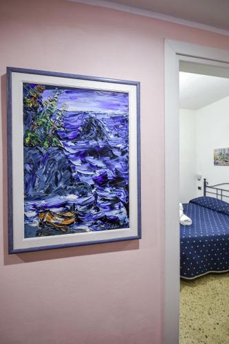 a painting hanging on a wall next to a bedroom at Albergo Al Carugio in Monterosso al Mare