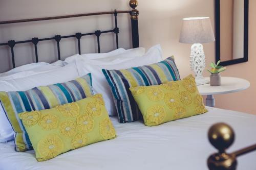 a bed with yellow and blue pillows on it at Station House Simondium in Simondium