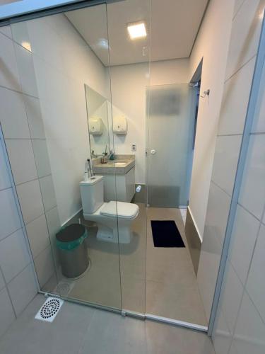 a bathroom with a toilet and a glass shower at Flamboyant Stay Rooms in Goiânia