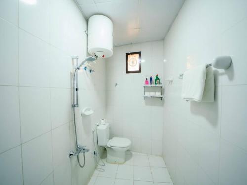 a white bathroom with a toilet and a shower at Desert Dune Farmhouse - By Seven Elements in Ras al Khaimah