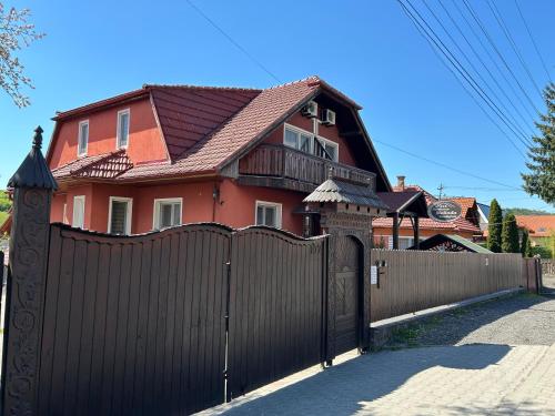 a house behind a fence with a wooden gate at Pensiunea Melinda in Praid