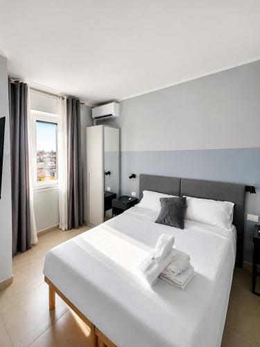 a bedroom with a large white bed with towels on it at Suite Panoramica - Novara Centro in Novara