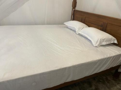 a bed with white sheets and two pillows on it at Elysian Riverside in Weligama