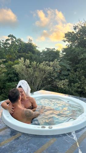 a man and a woman in a hot tub at Chalés Pura Vida in Itacaré