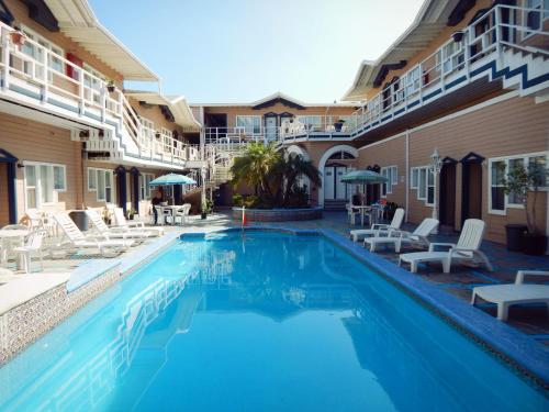 a swimming pool with white chairs and a hotel at Hotel Villa Fontana Inn in Ensenada