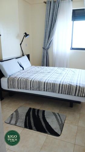 a bedroom with a bed with a rug and a window at Kigo Perch in Kampala
