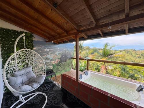 a balcony with a swing and a tub with a view at EDYMA Cabaña con JACUZZI in Guatapé
