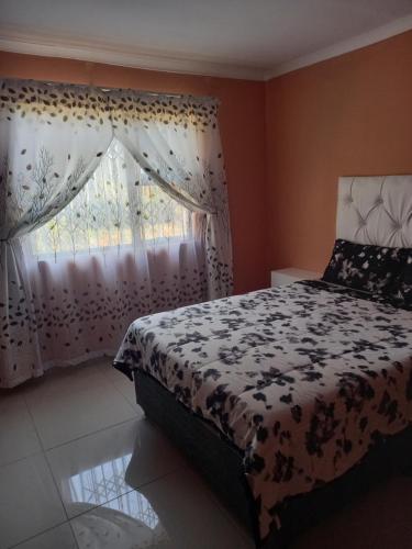 a bedroom with a bed and a window with curtains at Ocean Wave Chalets Unit 1 in Hibberdene