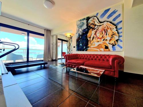 a living room with a red couch and a painting at Milazzo. Intero alloggio in affitto in Milazzo