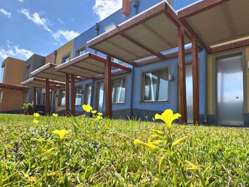 Eine Häuserreihe mit gelben Blumen im Gras in der Unterkunft ibis Styles Catania Acireale in Acireale