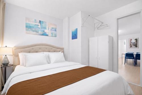 a white bedroom with a large bed and a dining room at Cozy 4BD Unit in Lower Manhattan in New York