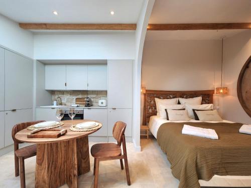 a bedroom with a bed and a table and a kitchen at Suite Amoriya in Camblanes-et-Meynac