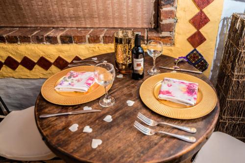 a wooden table with two slices of cake and wine glasses at Hotel Boutique Guatika in Tibasosa