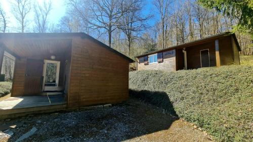 a small wooden building with a porch and a house at Chalet LE BAUSOY in Tournavaux