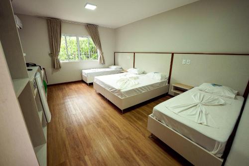 a hotel room with two beds and a window at Ody Park Resort Hotel in Iguaraçu