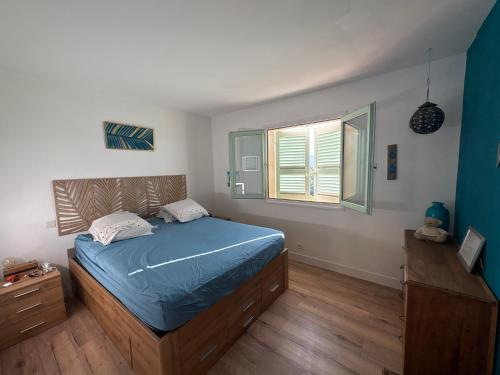 a bedroom with a blue bed and a window at vue sur le golfe de Saint Florent in Saint-Florent