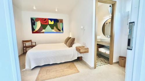 a white bedroom with a bed and a mirror at La Floristería Zahora in Zahora