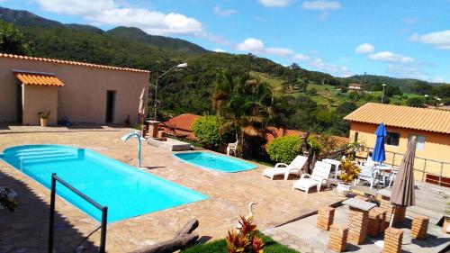 a pool in a yard with chairs and a house at Pousada Só Alegria in Mario Campos