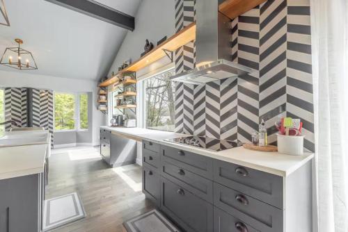 a kitchen with gray cabinets and a checkered wall at 5-Br Villa on Lake Labelle Chalet Jacob in Labelle
