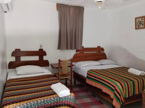 a bedroom with two beds and a window with a blanket at Hostal Doña Chava in Pedernales