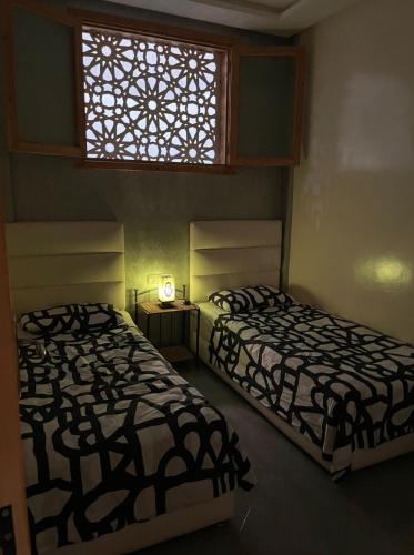 two beds in a room with a window at Appartement agadir centre in Agadir