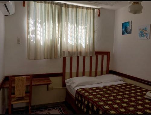 a small bedroom with a bed and a window at Hostal Doña Chava in Pedernales
