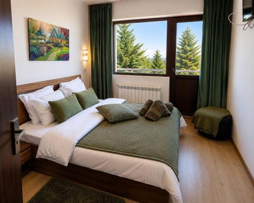 a bedroom with a large bed and a window at Семеен хотел Forest Retreat Mountain Resort in Kyustendil