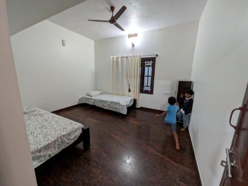 a young child is standing in a room with two beds at Cherry guest House Shringeri ,koppa rural in Chikmagalur