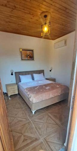 a bedroom with a large bed with a wooden ceiling at Vila Nakaj Guest House in Gjirokastër