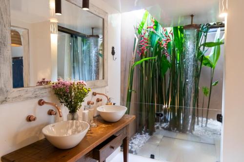 a bathroom with two sinks and a large plant at Casa La Torre Hotel Boutique in Trancoso
