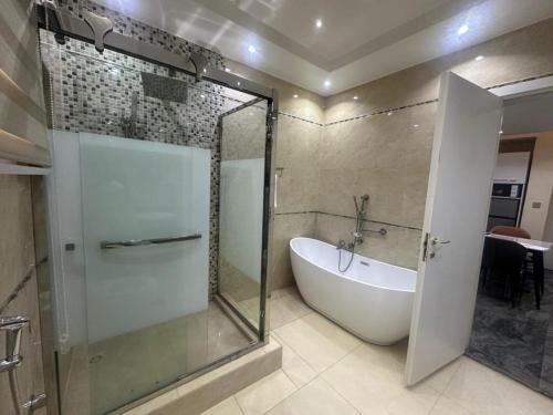 a bathroom with a glass shower and a bath tub at Peev Apartements in Abuja