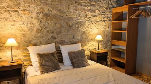 a bedroom with a bed with two lamps and a stone wall at Le Moulin des Salces in Saint-Privat