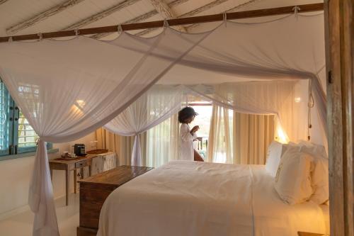 a woman standing in a bedroom with a large bed at Casa La Torre Hotel Boutique in Trancoso