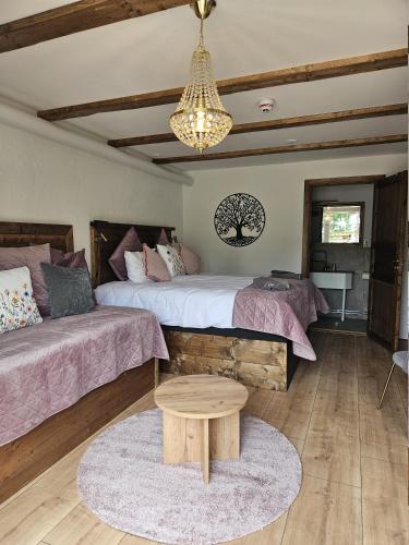 a bedroom with two beds and a table and a chandelier at Hotell & Spa Lögnäs Gård in Laholm