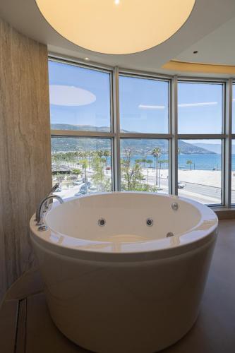 a large bath tub in a room with a large window at Quartz Hotel Vlore in Vlorë